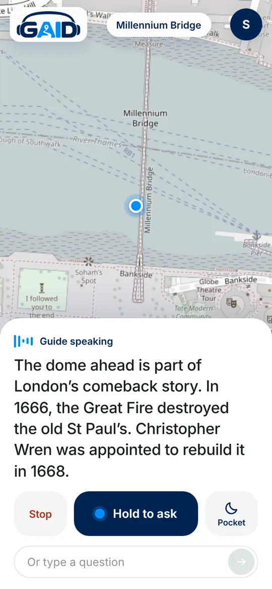 The GAID app on a phone during a walk across Millennium Bridge: a map with your position, and the guide's words about St Paul's as it speaks them, with Stop, Hold to ask and Pocket buttons.
